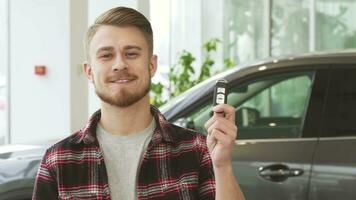 Attractive young man smiling holding car keys posing at the automotive dealership video