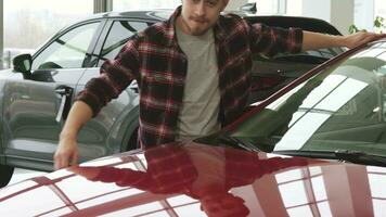 Joyful bearded handsome man embracing his new auto at the dealership salon video