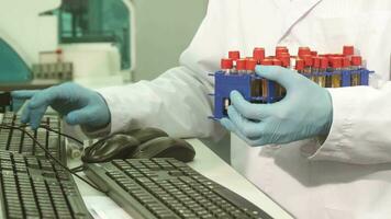 The laboratory worker rewrites the names of the test tubes to the computer video