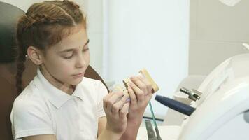 un curioso niña es jugado con un artificial mandíbula en el del dentista oficina video