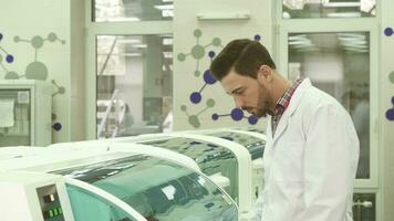 une Jeune laboratoire assistant étroitement observe le travail de le laboratoire centrifuger video