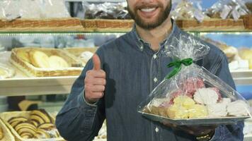 abgeschnitten Schuss von ein glücklich bärtig Mann zeigen Daumen oben beim das Bäckerei video