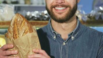 cortada fechar acima f uma barbudo homem sorridente segurando uma pão do fresco pão video