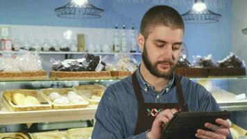 hermoso profesional masculino panadero utilizando digital tableta a su Tienda video