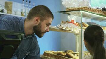 atractivo masculino panadero hablando a un pequeño niña a su panadería Tienda video