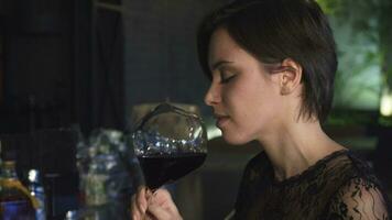 Close up of a gorgeous brunette enjoying drinking wine at the bar smiling to the camera video