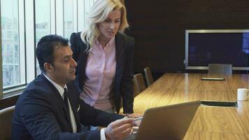 A concentrated man and woman watching their project on a laptop and discussing it video