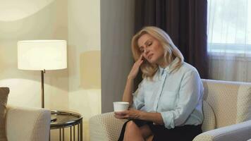 Tired girl sitting on chair and drinking coffee video