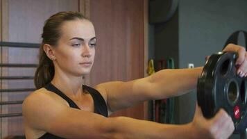 The young girl is doing exercises in the gym using a special round dumbbell video