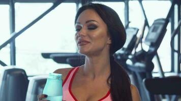 schön Frau ist Trinken Wasser im das Fitnessstudio video