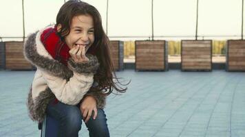 A happy girl laughs hard while sitting on the street video