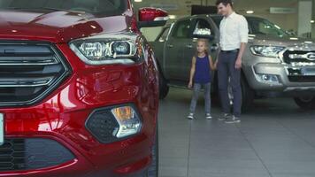 Kind father with a daughter are watching cars in the automobile salon video