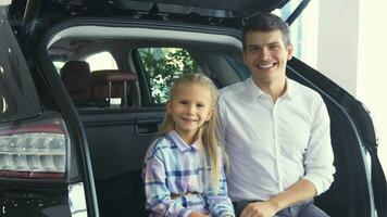 encantador padre y hija son sentado en el abierto maletero de el coche video