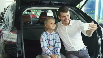 A young father with a daughter makes selfie on the background of a car video