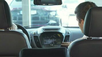 Funny dad with his daughter sit in the front seats and look at the small screen of the car video