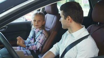 The young father communicates with the daughter sitting in the car video