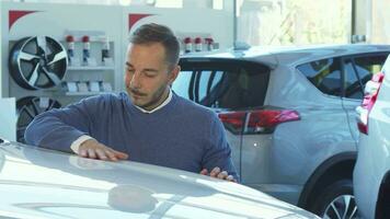 negocio hombre examina el coche en el coche sala de exposición video