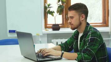 A young man is sitting at a computer in an educational institution video