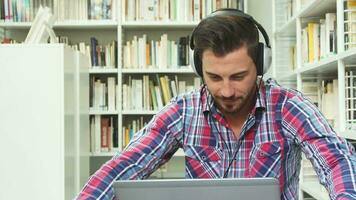 jovem cara ouvindo para música em fones de ouvido em computador portátil video