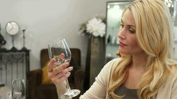 The blonde woman chooses a glass for wine video