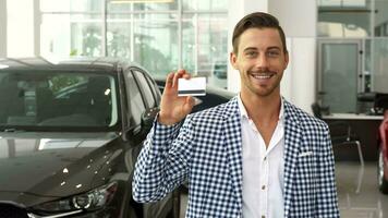 el contento nuevo coche comprador muestra su crédito tarjeta video