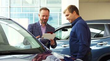 The seller in the suit shows the customer the car interior video