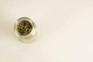 a jar filled with dried herbs on a white surface photo