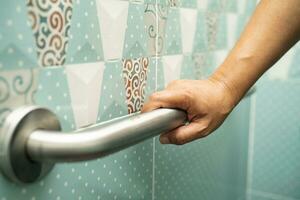 Asian elderly woman use bathroom handle security in toilet, healthy strong medical concept. photo