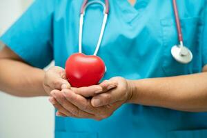 médico sosteniendo un corazón rojo en la sala del hospital, concepto médico fuerte y saludable. foto