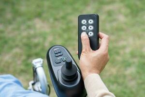 Asian woman patient on electric wheelchair with remote control at hospital. photo