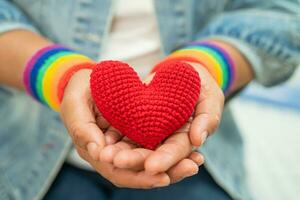 dama asiática con pulseras con la bandera del arco iris y un corazón rojo, símbolo del mes del orgullo lgbt celebran anualmente en junio las redes sociales de gays, lesbianas, bisexuales, transgénero, derechos humanos. foto