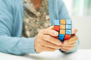 bangkok, Tailandia agosto 14, 2023 Alzheimer enfermedad anuncio, asiático mayor mujer paciente jugando rubik cubo juego a práctica cerebro formación para demencia prevención. foto