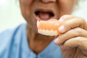 Asian elderly woman patient holding to use denture, healthy strong medical concept. photo