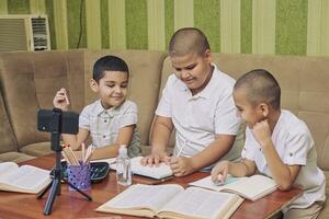 hermanos estudiando a hogar durante el pandemia foto