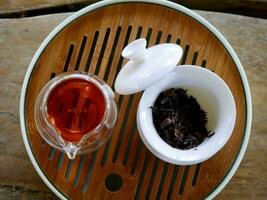 tea from glass teapot on wooden serving tray, Tea making process, Glass teapot at the tea ceremony close up, A cup of balance filled with tea, Healthy fermented puerh herbal teachinese ceremony photo