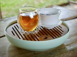 tea from glass teapot on wooden serving tray, Tea making process, Glass teapot at the tea ceremony close up, A cup of balance filled with tea, Healthy fermented puerh herbal teachinese ceremony photo