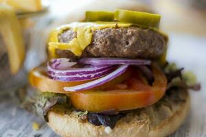 Selective focus close-up shot of a vegan burger bun with plant-based cheese, onion and tomato photo