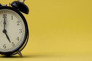 Analog alarm clock displaying five o'clock on a yellow background with copy space photo