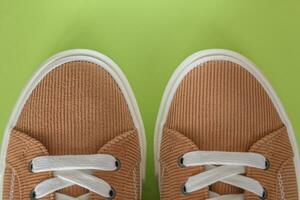 Beige corduroy sneakers on a green background photo