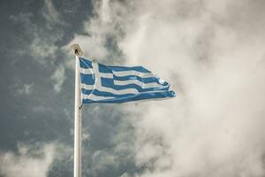 Waving Greek flag against a blue sky with clouds photo