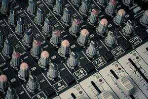 Closeup and detail of audio mixing console with faders and knobs photo