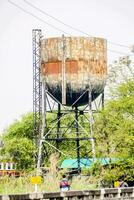 an old rusty water tower on the side of the road photo