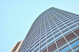 Glass building with transparent facade of the building and blue sky. Structural glass wall reflecting blue sky. Abstract modern architecture fragment. Contemporary architectural background. photo