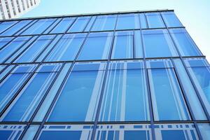 Glass building with transparent facade of the building and blue sky. Structural glass wall reflecting blue sky. Abstract modern architecture fragment. Contemporary architectural background. photo