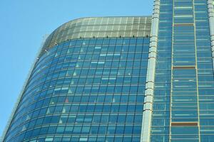 Glass building with transparent facade of the building and blue sky. Structural glass wall reflecting blue sky. Abstract modern architecture fragment. Contemporary architectural background. photo