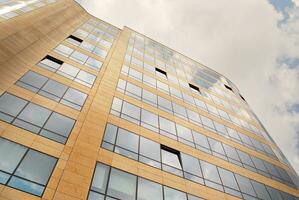 Glass building with transparent facade of the building and blue sky. Structural glass wall reflecting blue sky. Abstract modern architecture fragment. Contemporary architectural background. photo