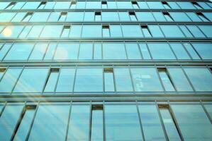 vaso edificio con transparente fachada de el edificio y azul cielo. estructural vaso pared reflejando azul cielo. foto