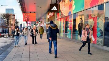 Warsaw, Poland. 5 December 2023. Residents and guests walk along the central street of city. People on sidewalk on with shops. photo