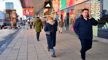 Warsaw, Poland. 5 December 2023. Residents and guests walk along the central street of city. People on sidewalk on with shops. photo