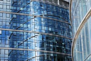 Glass building with transparent facade of the building and blue sky. Structural glass wall reflecting blue sky. Abstract modern architecture fragment. Contemporary architectural background. photo